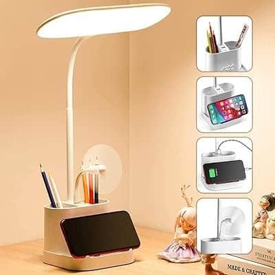 Adjustable LED desk lamp with wireless charging, phone holder, and storage tray for a modern workspace.